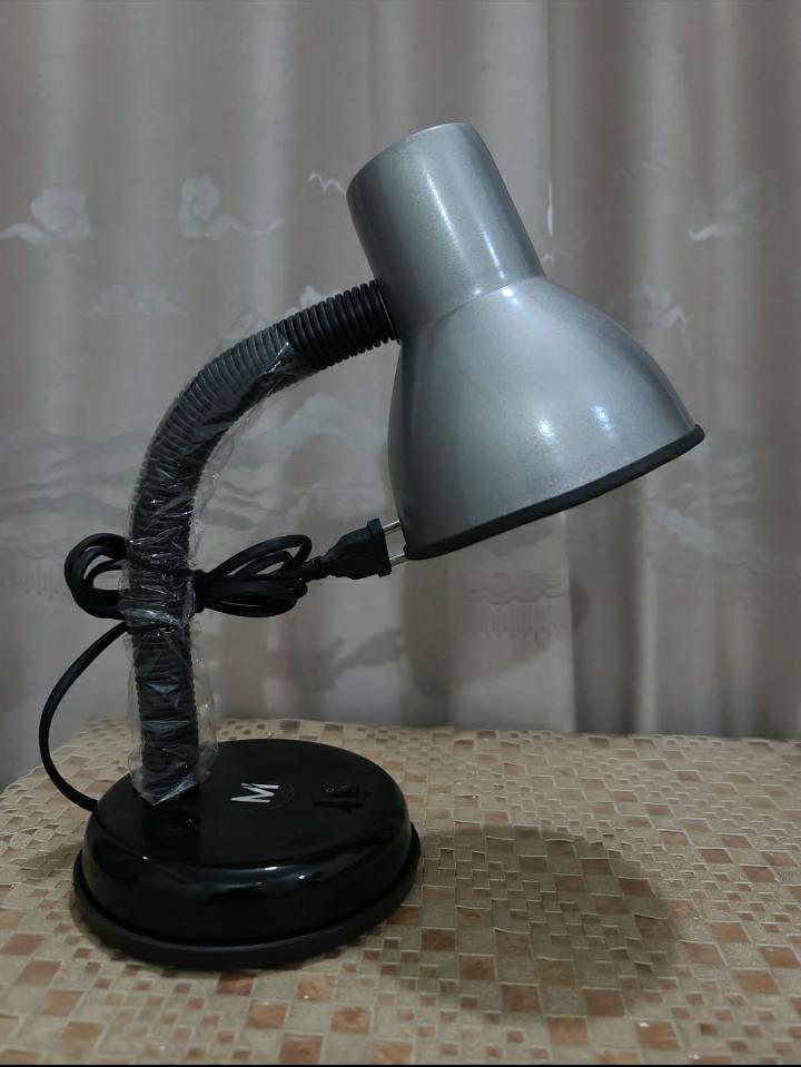 Gray desk lamp with flexible neck on a tiled surface